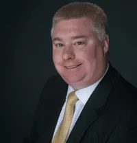 Tim M. from PracticeERP, smiling in a professional suit with a yellow tie, representing the firm's commitment to enhancing CPA firm efficiency and productivity.