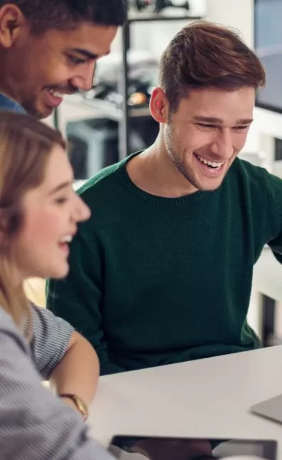 Group of professionals collaborating and smiling while reviewing data on a laptop, emphasizing teamwork and productivity in a modern office setting, relevant to PracticeERP's focus on enhancing business performance and efficiency.