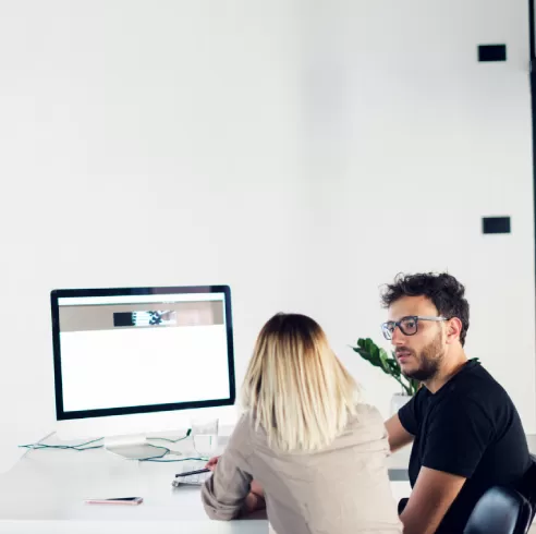 Two professionals collaborating at a desk, focusing on a computer screen displaying a business application, illustrating PracticeERP's technology solutions for CPA firms.