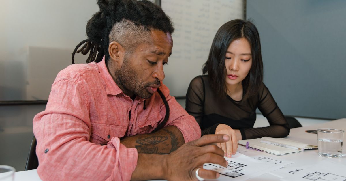 Two professionals engaged in planning during a business meeting, focusing on architectural designs.