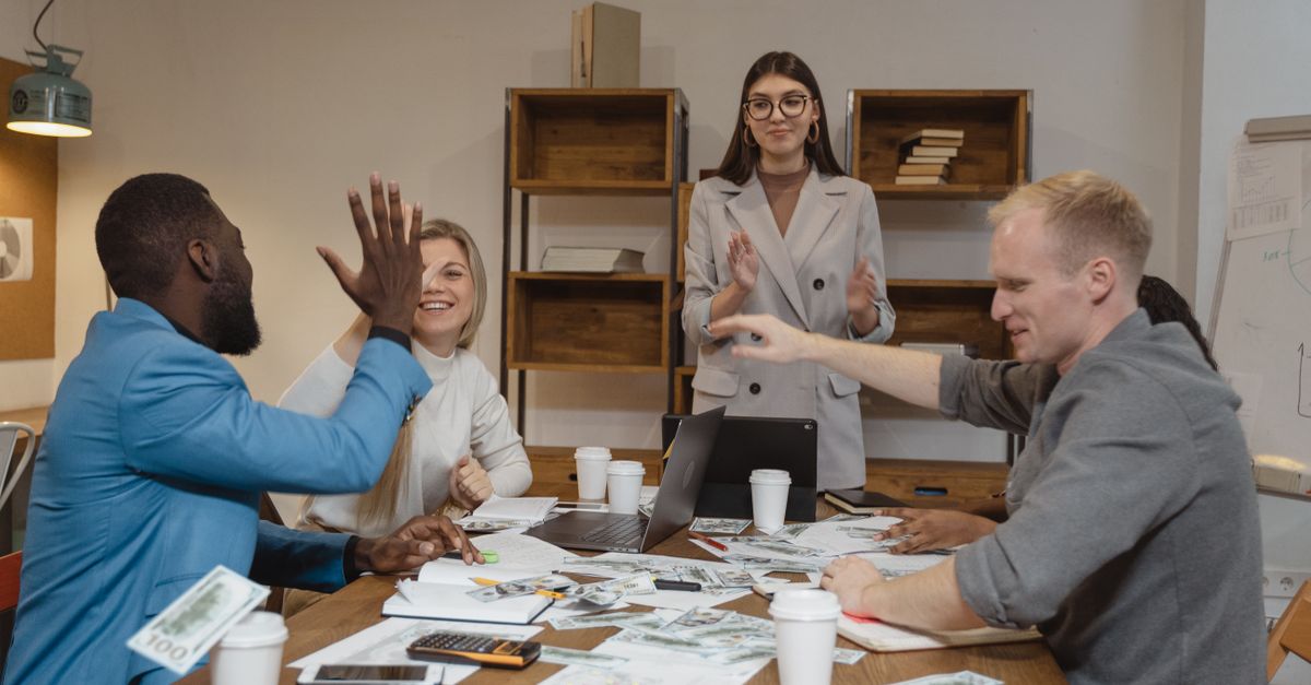 A multicultural team enjoying success during a collaborative business meeting in a modern office.