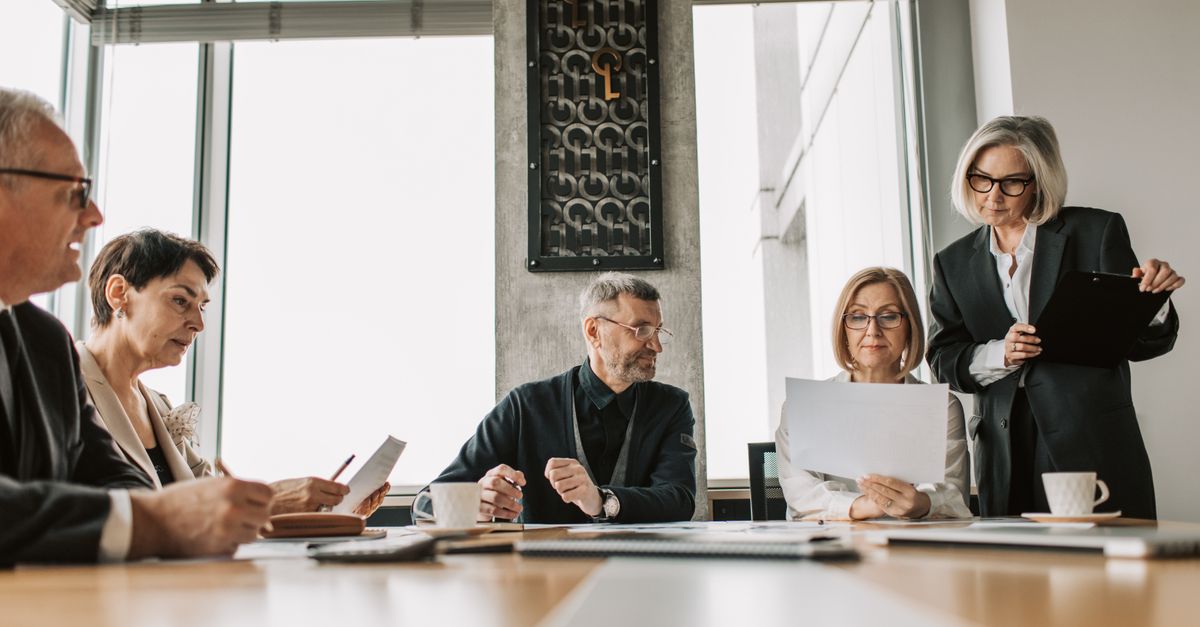 Business professionals discussing documents in a modern meeting room.