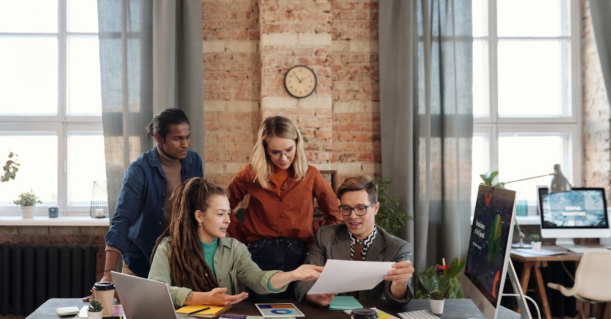 A diverse team of young professionals working on a business strategy in an urban office setting.