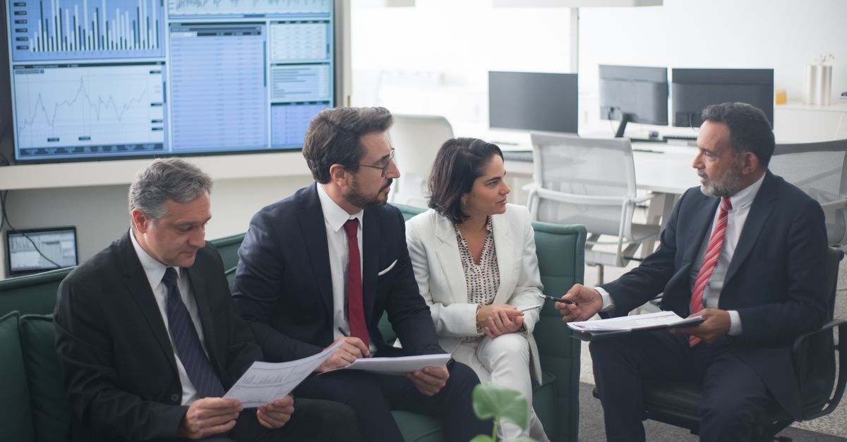 Group of business professionals discussing financial strategies in a modern office setting.