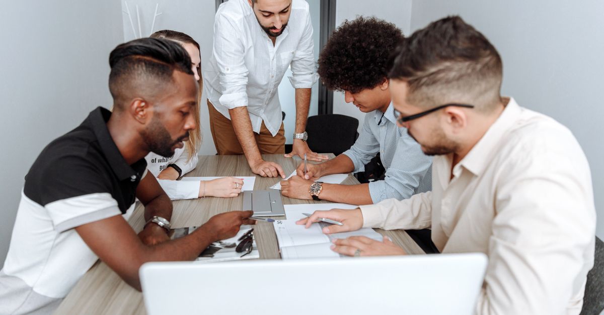 A diverse group of professionals actively collaborating at an office table during a business meeting.