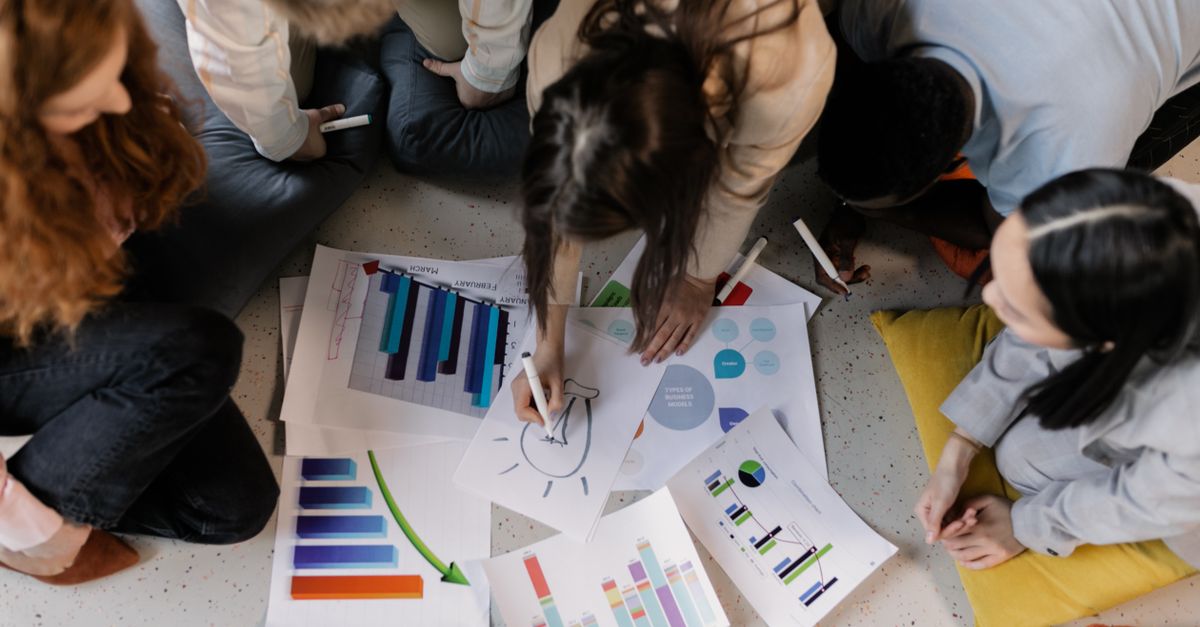 Overhead view of diverse team brainstorming on business strategy using charts and graphs.