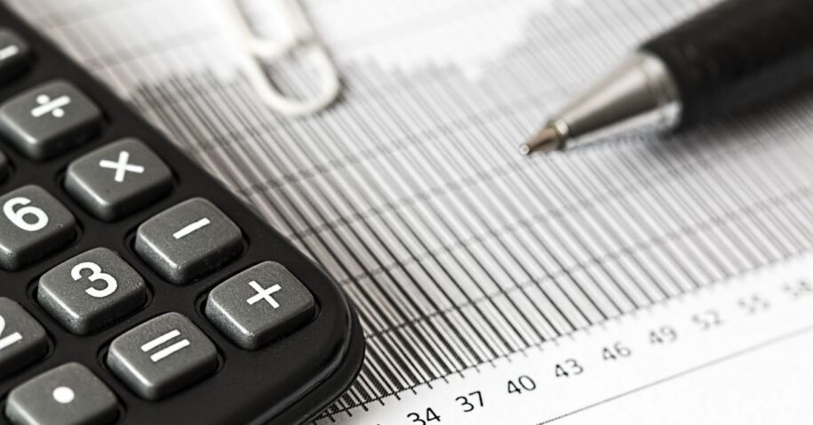 Close-up of a calculator and pen on a bar graph, representing finance and accounting.