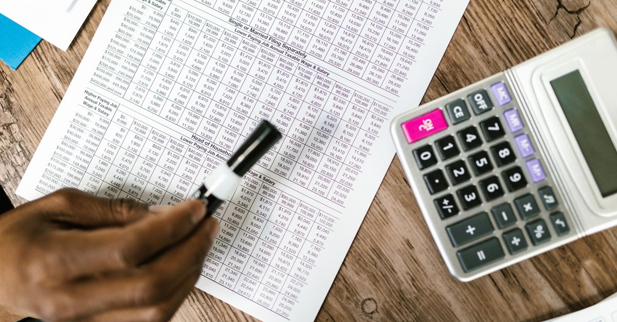 Close-up of tax documents and calculator on wooden table, highlighting financial analysis.