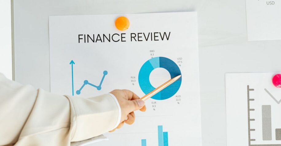 Close-up of hand pointing at finance report with charts and graphs on paper.