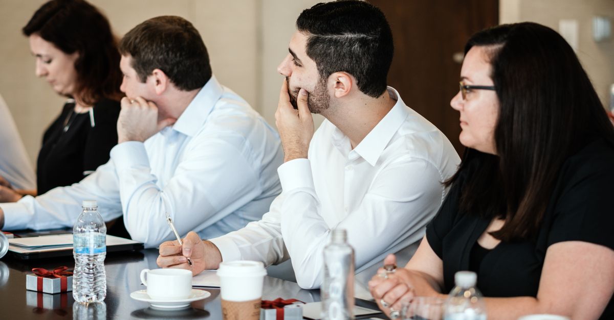 A diverse group of professionals engaged in a business meeting, collaborating and taking notes.