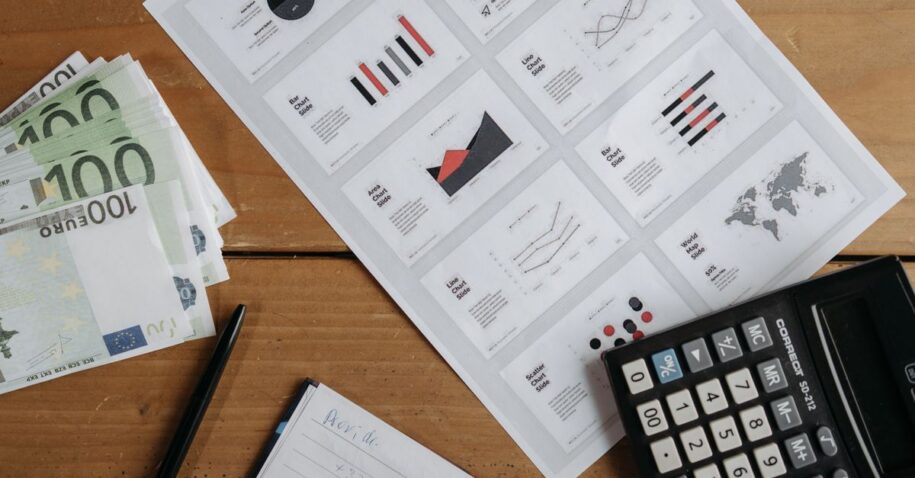 Euro banknotes, graphs, and calculator on a wooden table setup for financial analysis.