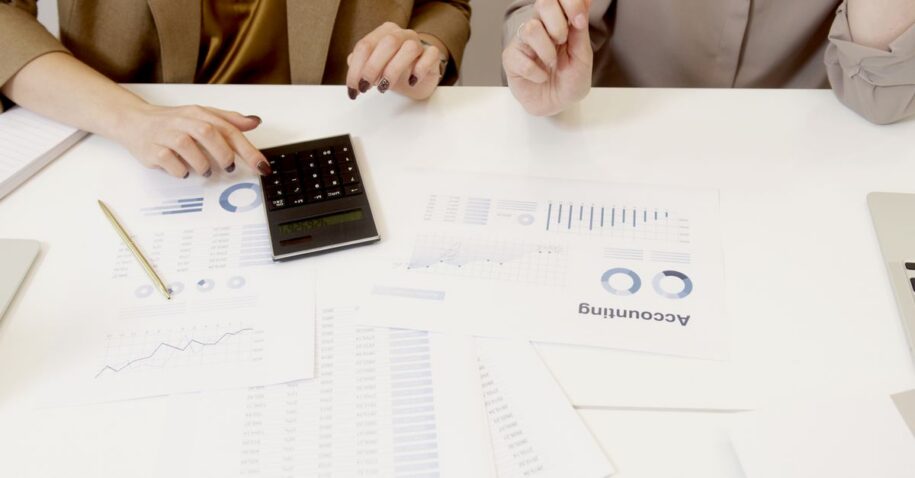 Two professionals analyzing financial documents with a calculator.