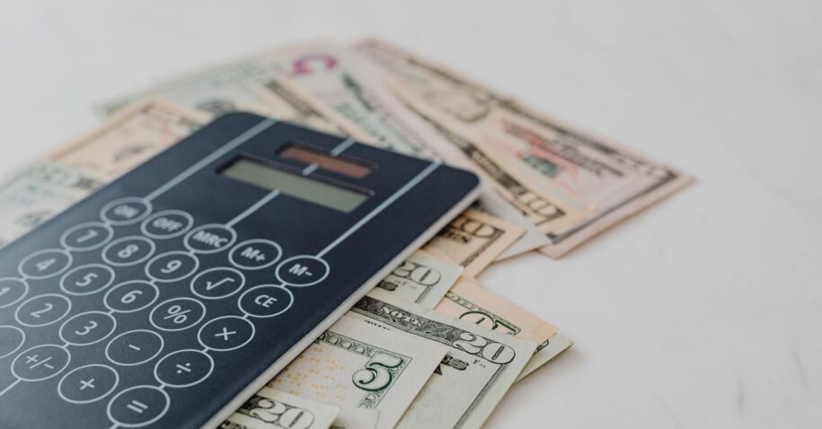 A close-up of a calculator and US dollar banknotes, symbolizing financial calculation and budgeting.