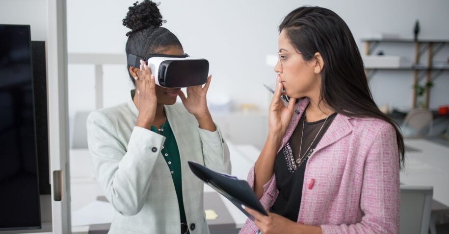 Two professional women collaborating using VR technology in a modern office setting, showcasing innovation.
