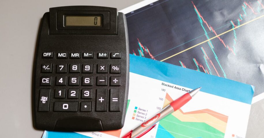 Calculator and pen on a desk with financial charts, showcasing analysis and business planning.