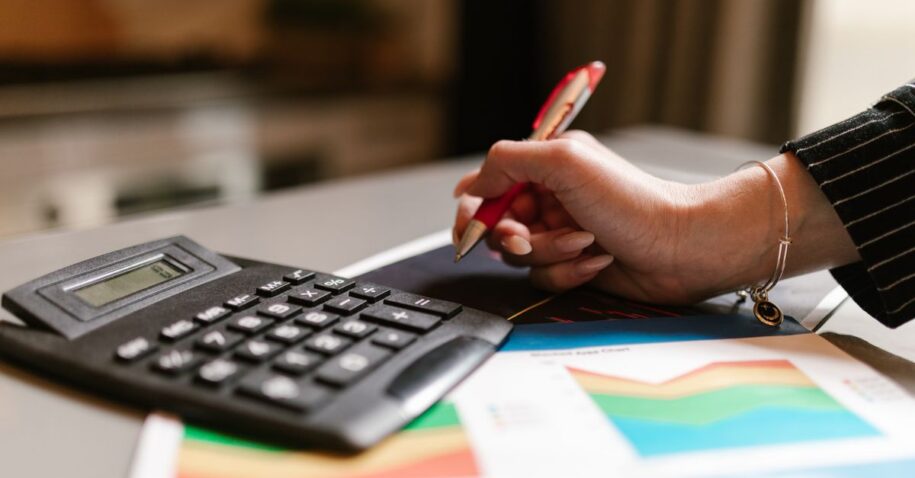 A business professional uses a calculator and documents during a workspace task.