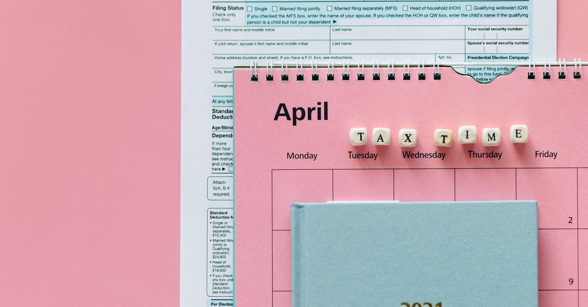 Flat lay image of tax forms, calendar, and 'tax time' reminder on a pink background.
