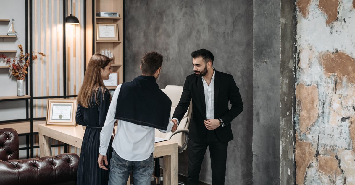 Business professionals discussing in a stylish, modern office setting with a handshake agreement.