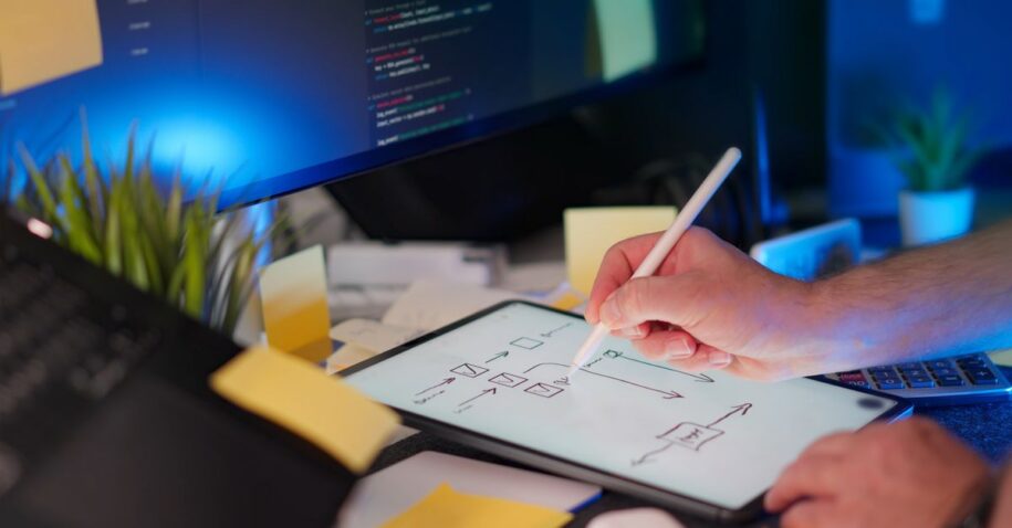 A vibrant workspace featuring digital sketching on a tablet and code on a monitor, showcasing a tech-savvy environment.