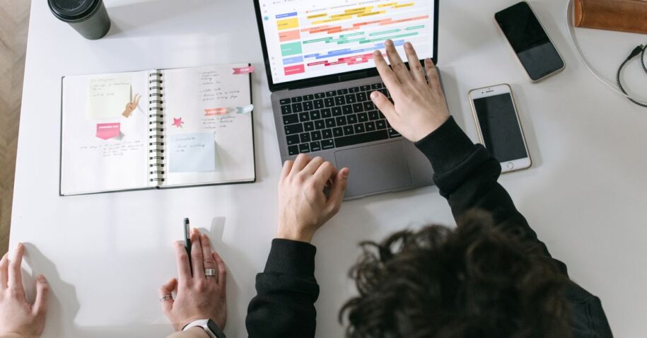 Two people collaborating on a laptop and planner at a vibrant modern office desk.