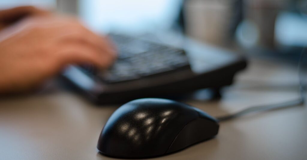 Blurry background with a focus on a computer mouse in an office setting.