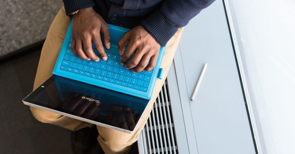 A person typing on a tablet with a blue keyboard indoors, highlighting remote work.