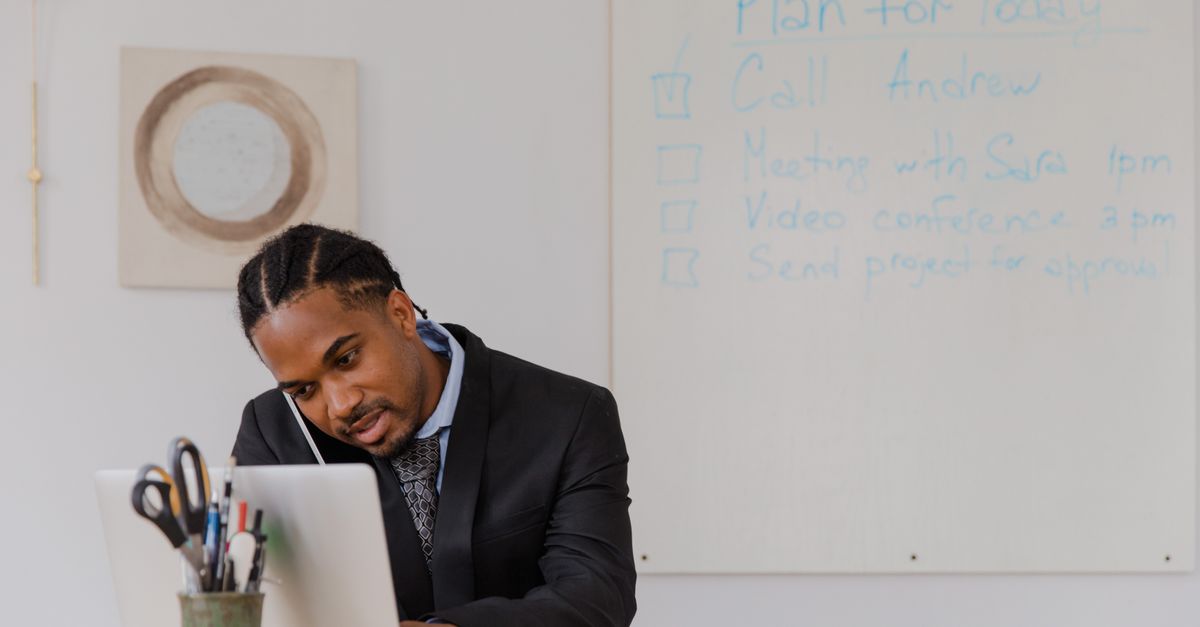 Businessman at his desk in an office working on a laptop and making phone calls.