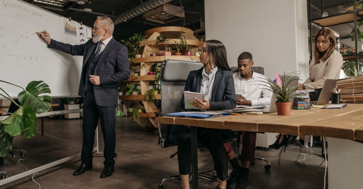 Business professionals engage in a team meeting with a whiteboard presentation in a modern office.