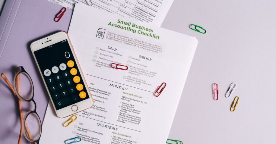 Top view of accounting essentials including smartphone, eyeglasses, and paperwork.