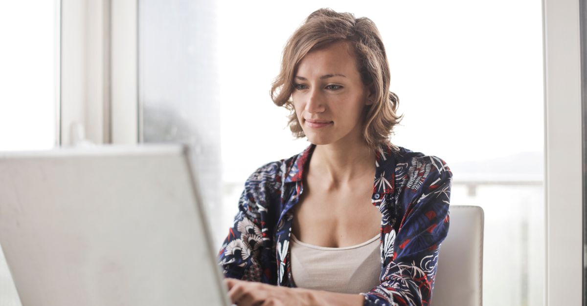 A woman typing on a laptop in a bright, modern home office setting.